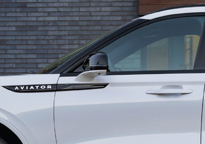 The driver’s side door and fender badging of a white 2026 Lincoln Aviator® SUV are showcased. | Cummins Lincoln in Weatherford OK