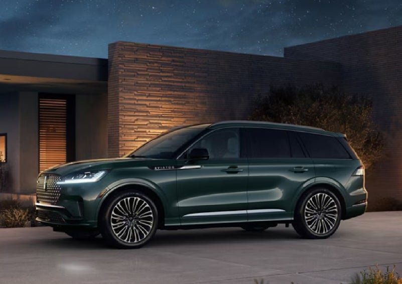 A green 2027 Lincoln Aviator® SUV is parked outside a contemporary home. | Cummins Lincoln in Weatherford OK