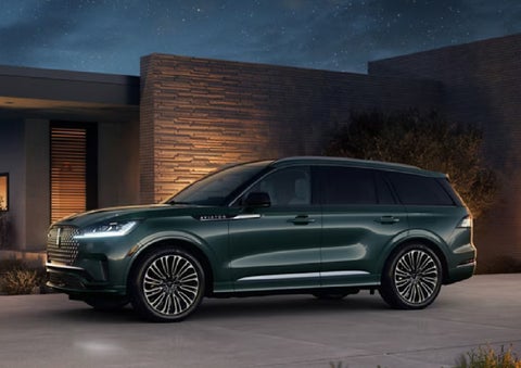 A green 2027 Lincoln Aviator® SUV is parked outside a contemporary home. | Cummins Lincoln in Weatherford OK