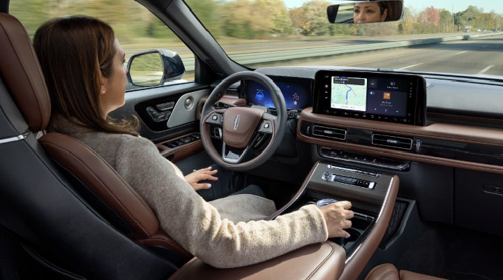 A 2027 Lincoln Aviator® SUV is being driven hands-free on a highway lined with trees. | Cummins Lincoln in Weatherford OK
