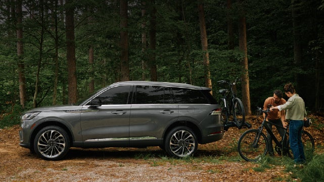 A father and son load e-bikes on a bike rack attached to a 2027 Lincoln Aviator® SUV. | Cummins Lincoln in Weatherford OK